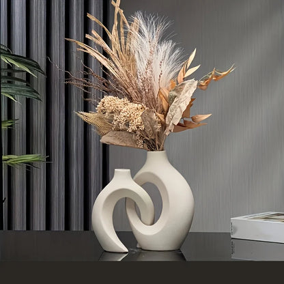 Decorative vase with dried flowers on a reflective surface with a gray curtain background