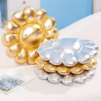 Gold and silver balloon-like decorative items on a white surface with a blue wall in the background.