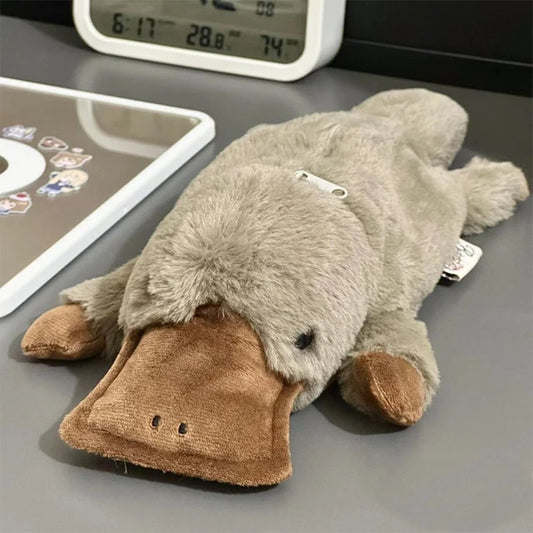 Plush toy resembling a platypus on a desk with a digital clock in the background