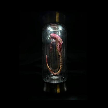 Alien creature model inside a glass dome on a black background