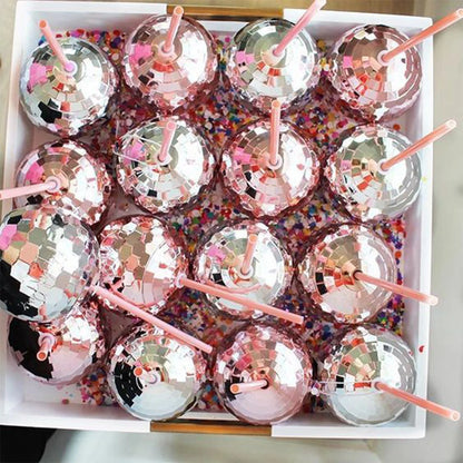 Box of disco ball lollipops with straws on a colorful confetti background