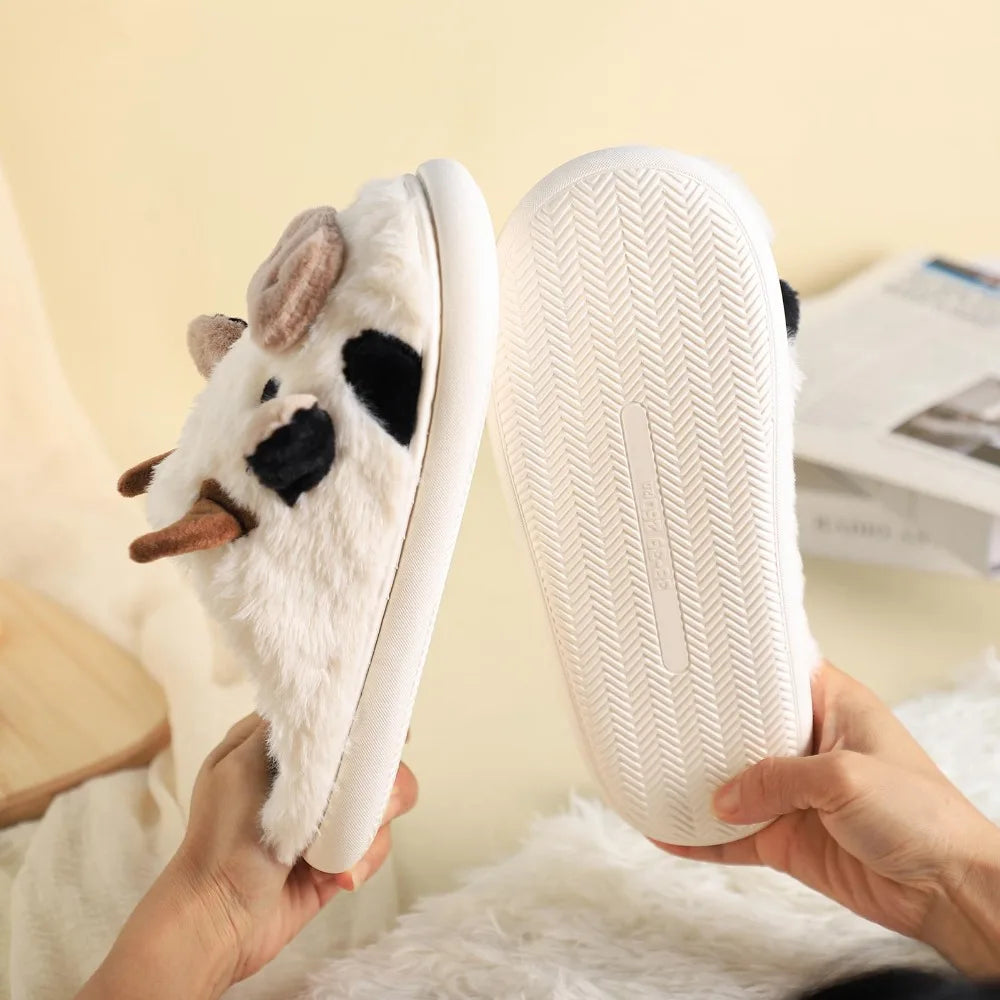 White plush slippers with animal design held by a person against a light background