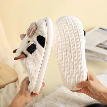 White plush slippers with animal design held by a person against a light background