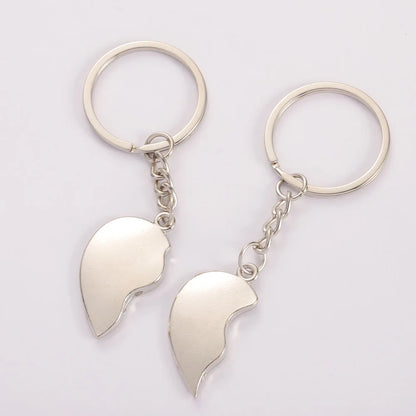 Two silver keychains shaped like half-hearts on a light gray background