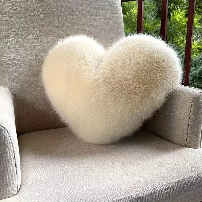 Heart-shaped fluffy pillow on a gray chair with a blurred green outdoor background