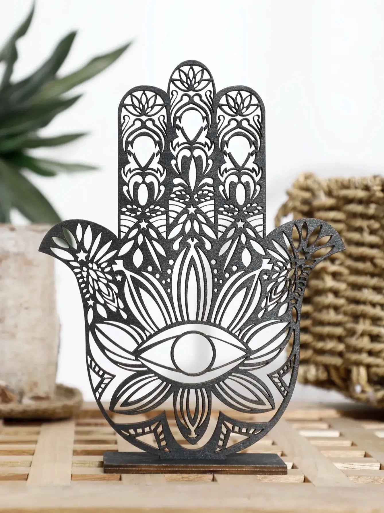 Decorative metal Hamsa hand with intricate designs on a wooden surface.
