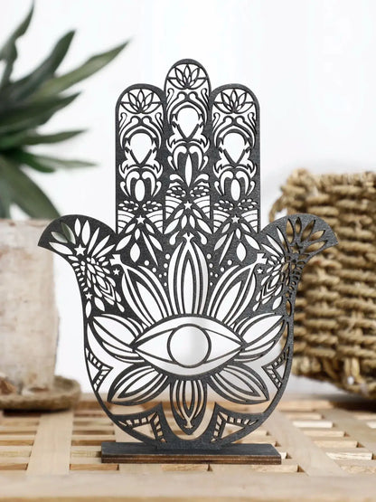 Decorative metal Hamsa hand with intricate designs on a wooden surface.
