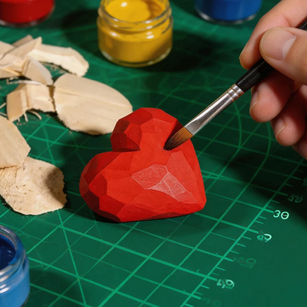 Hand painting a red geometric heart sculpture with a brush on a green cutting mat.