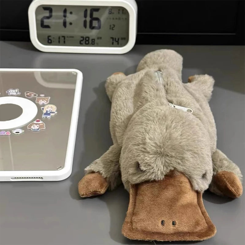 Plush toy resembling a cartoon character on a surface with a digital clock and tablet in the background.
