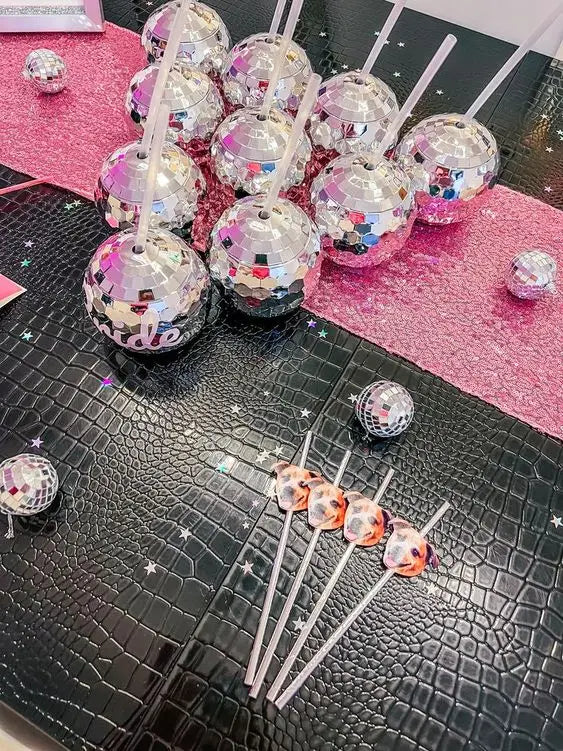 Decorative lollipops with disco ball-like tops on a black textured surface.