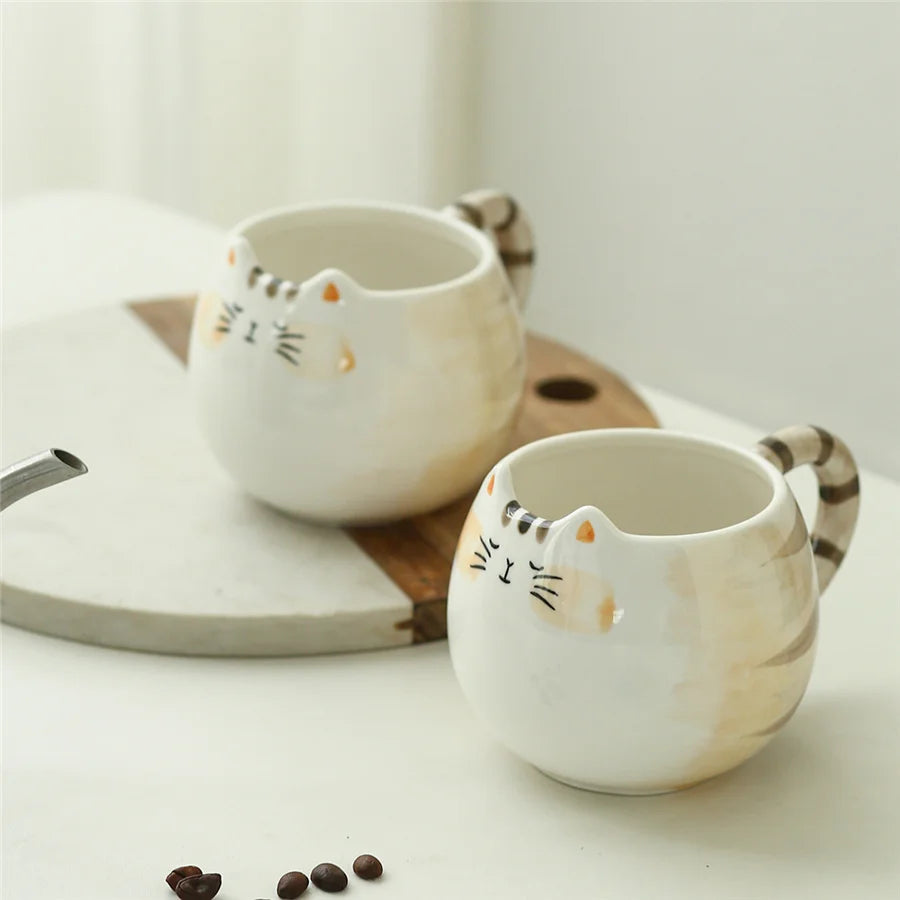 Two white ceramic mugs with cat face designs on a wooden tray.