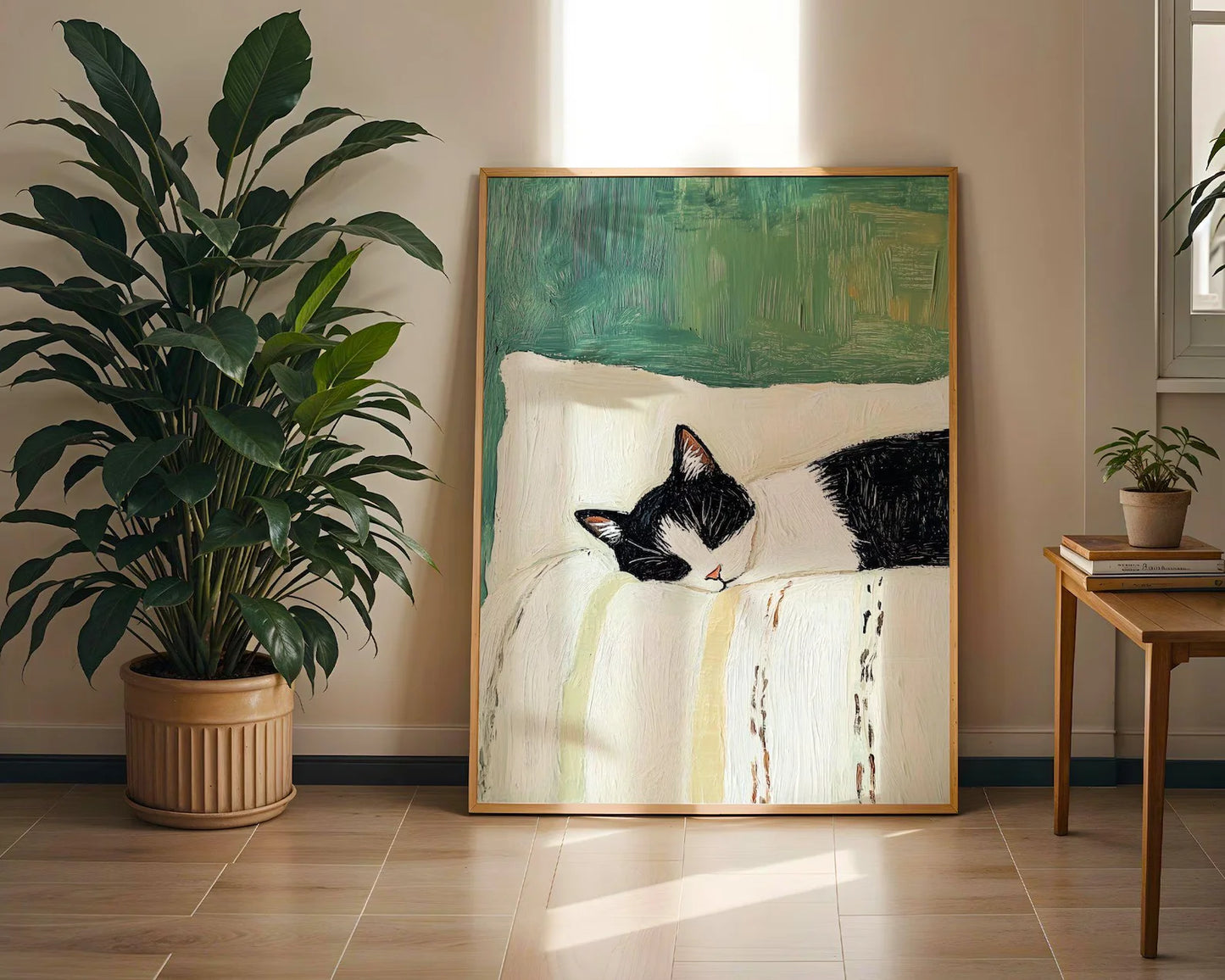 Framed artwork of a cat on a bed in a room with a plant and side table.