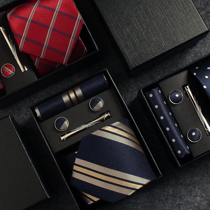 Collection of ties, cufflinks, and pocket squares in a black box on a dark surface.