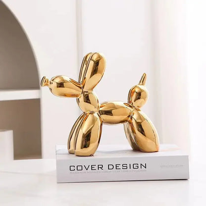 Gold balloon dog sculpture on a white surface with 'Cover Design' branding.