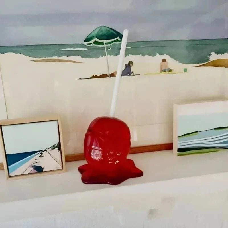Red glass sculpture with a beach scene painting in the background