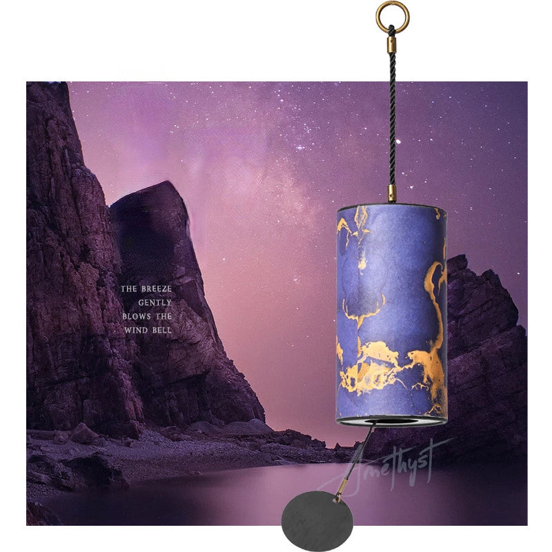 Decorative wind bell with gold designs against a purple sky and rocky landscape