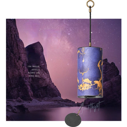Decorative wind bell with gold designs against a purple sky and rocky landscape