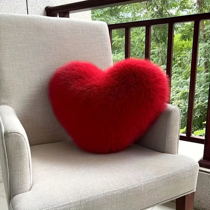 Red heart-shaped pillow on a gray chair with a blurred green outdoor background
