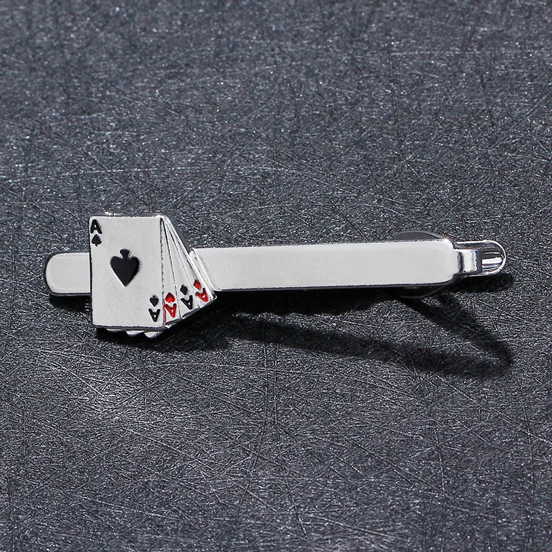 Silver tie clip with playing card design on a dark textured surface