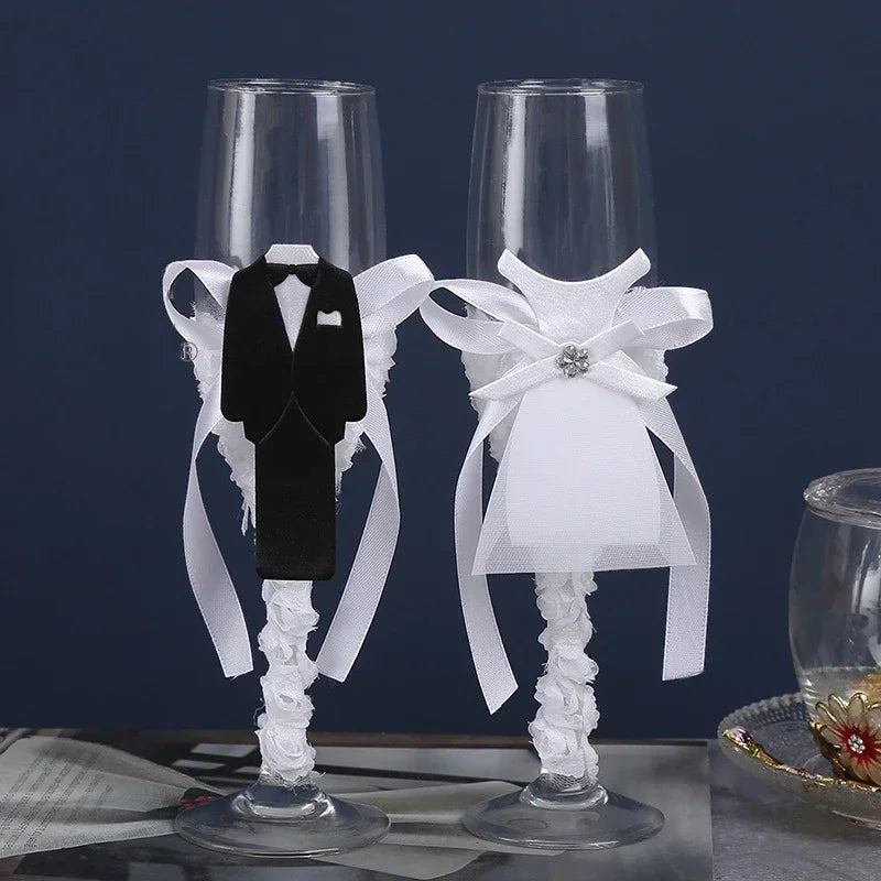 Two decorative champagne flutes with tuxedo and wedding dress designs on a dark background.