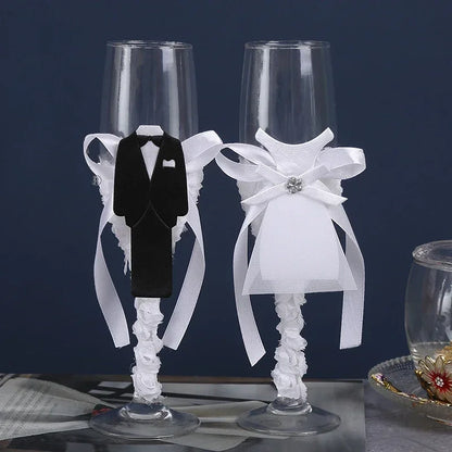 Two decorative champagne flutes with tuxedo and wedding dress designs on a dark background.