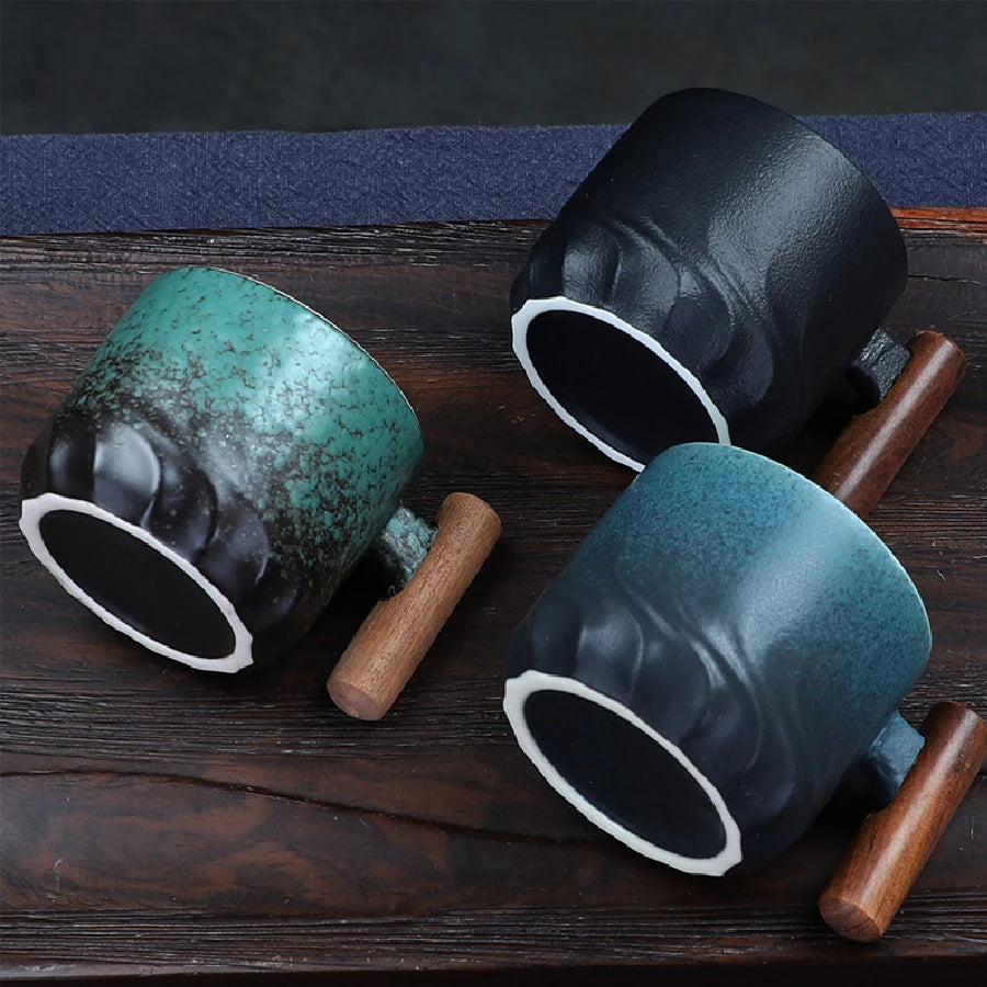 Three ceramic mugs with wooden handles on a dark wooden surface