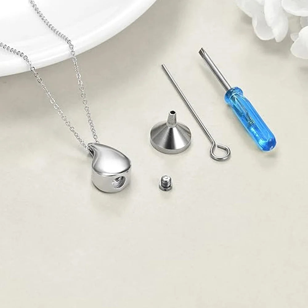 Silver pendant with chain, funnel, and screwdriver on a light surface