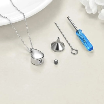 Silver pendant with chain, funnel, and screwdriver on a light surface