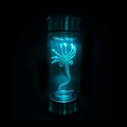 Glowing blue creature inside a transparent container on a black background