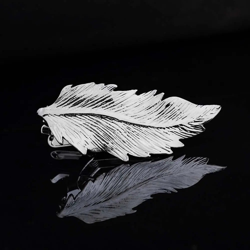 Silver feather-shaped brooch on a black background