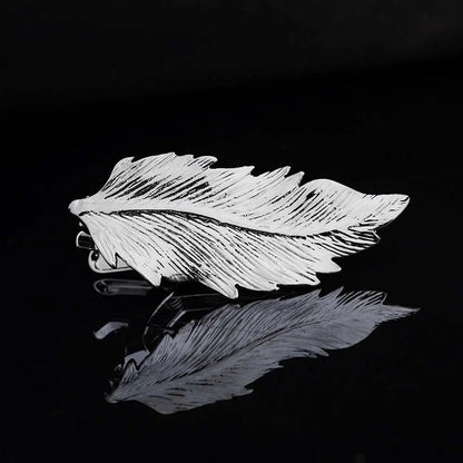 Silver feather-shaped brooch on a black background