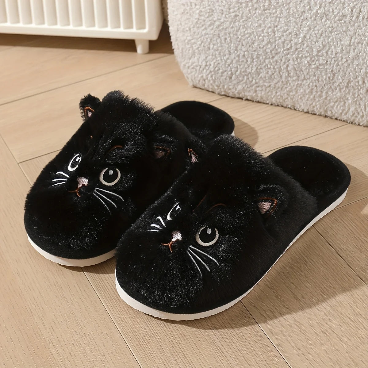 Black cat-shaped slippers on a wooden floor