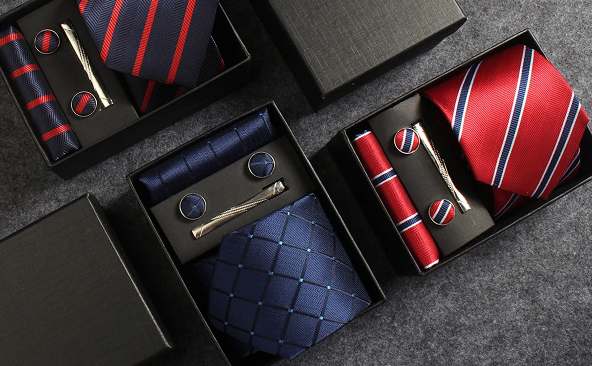 Collection of ties and accessories in black boxes on a gray surface
