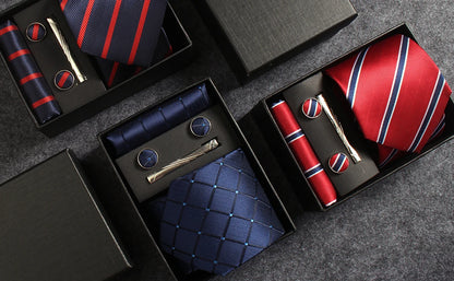 Collection of ties and accessories in black boxes on a gray surface