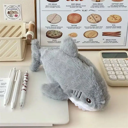 Gray plush shark toy on a desk with a chart and stationery items