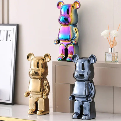 Three metallic bear figurines in gold, iridescent, and silver on a light-colored surface.