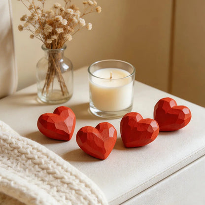 Red heart-shaped objects on a surface with a candle and vase in the background
