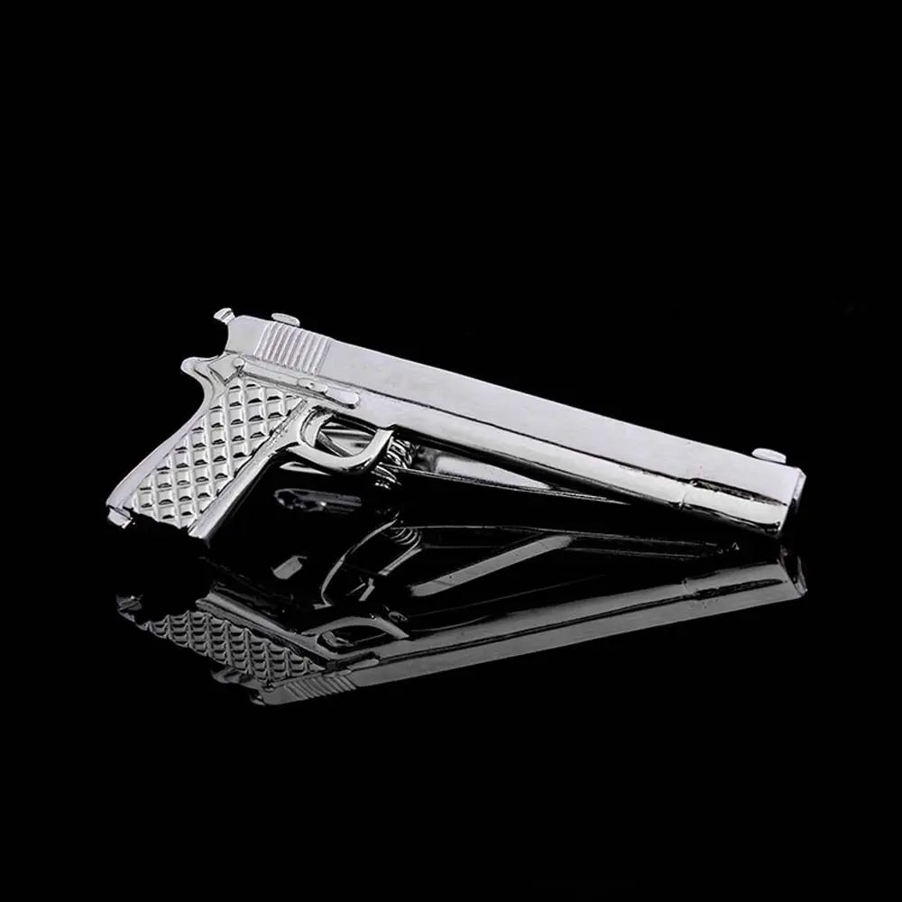 Metallic gun-shaped tie clip on a black background