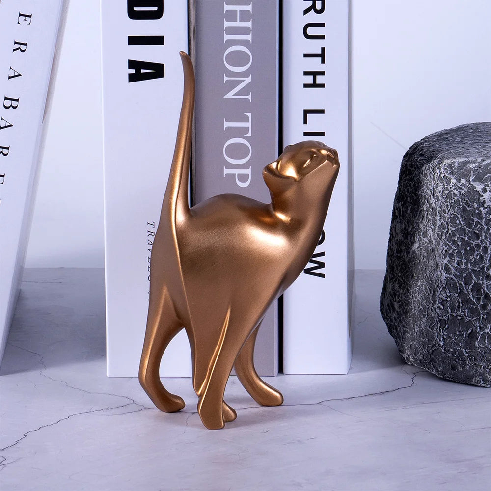 Bronze cat figurine on a light gray surface with books in the background