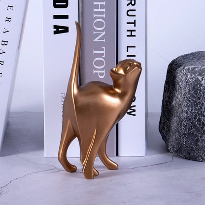 Bronze cat figurine on a light gray surface with books in the background