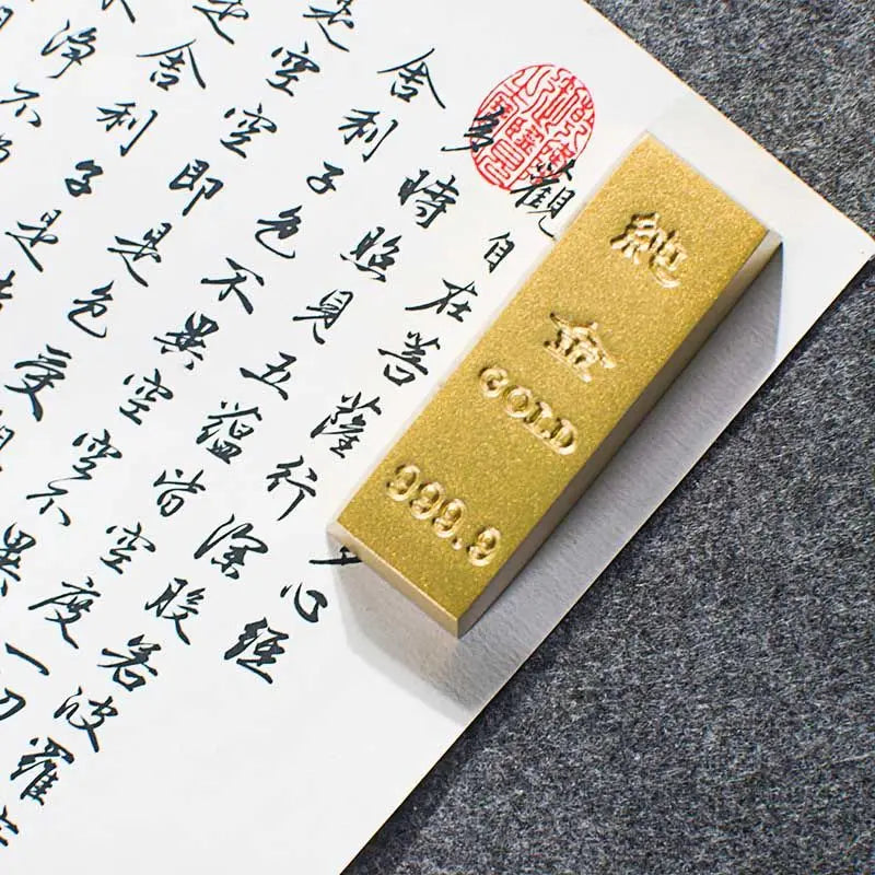 Gold bar with '999.9' purity mark on a piece of paper with calligraphy.