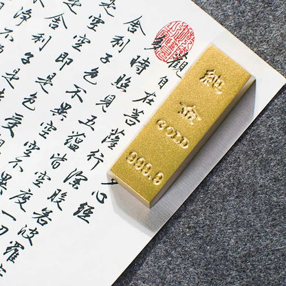 Gold bar with '999.9' purity mark on a piece of paper with calligraphy.