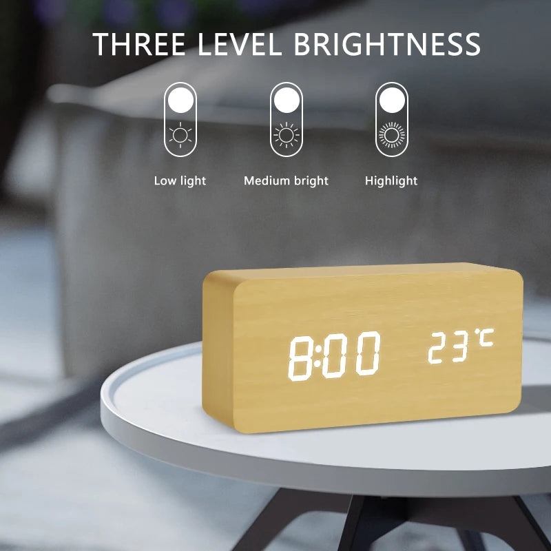 Wooden digital clock with LED display on a table, showing time and temperature, with three level brightness indicators above.
