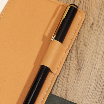 Black pen with gold clip on a brown leather case on a wooden surface