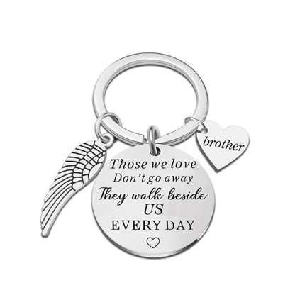 Silver keychain with angel wing, heart, and engraved message on a white background