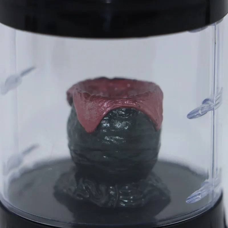 Close-up of a small dinosaur figurine inside a transparent container with a black lid.