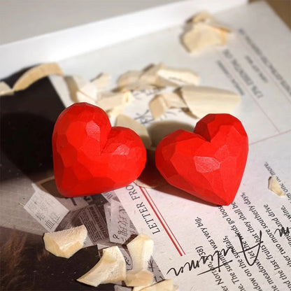 Red heart-shaped earrings on a newspaper background