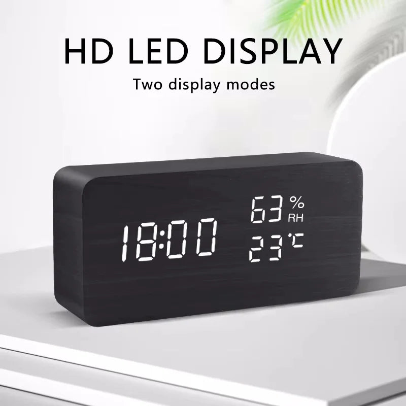 Black digital clock with LED display showing time, temperature, and humidity on a white surface.