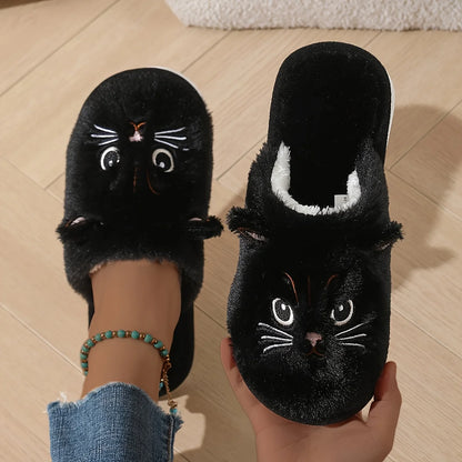 Black cat-themed slippers worn by a person on a wooden floor.