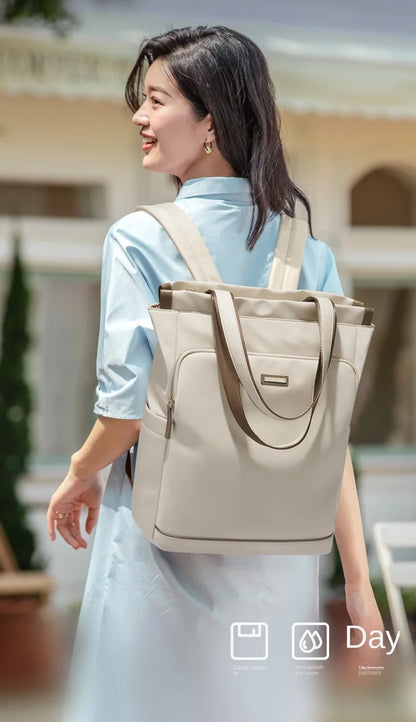 Woman carrying a beige backpack outdoors with a blurred background